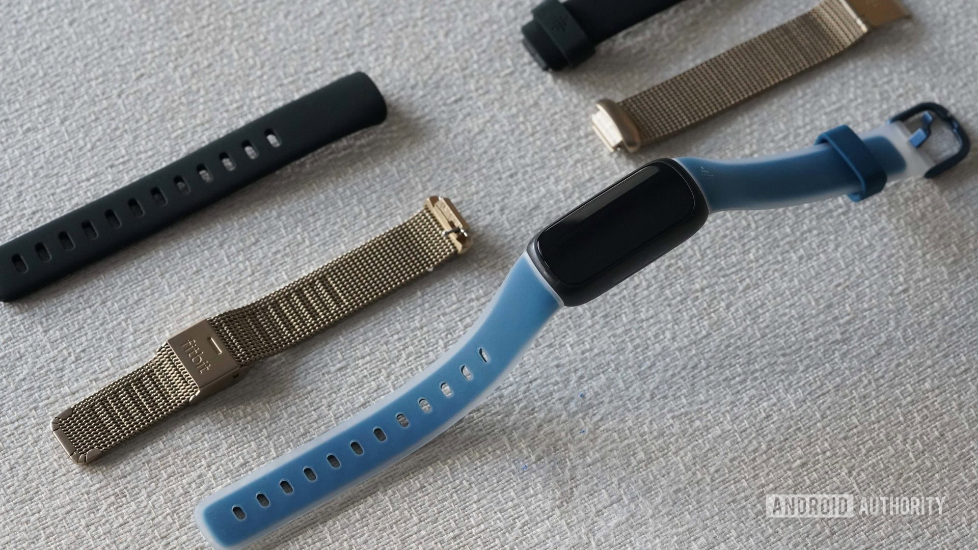 Fitbit Inspire 3 Accessories A Fitbit Inspire 3 and two alternative bands rest on a white fabric surface.